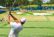 Tiger Woods swinging on at the PGA Golf Championship with crowd watching and photographers taking pictures