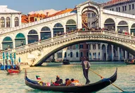Gondola with tourists in front of the Rialto bridge illustrating the Venice Biennale in Italy
