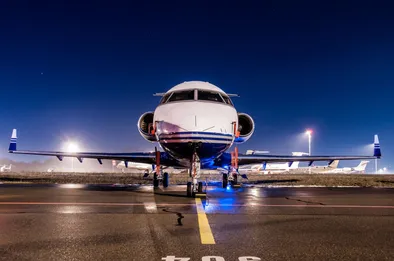 Vorderansicht eines Privatjets, der nachts auf der Landebahn wartet