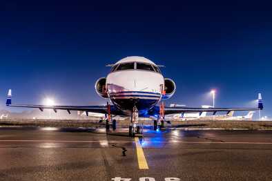 Front view of a private jet waiting on a runway at night