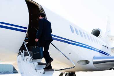 Business man boarding a private jet with a LunaJets branded bag