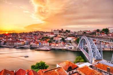 A stunning sunset view of Porto, showcasing the city's historic centre, the Dom Luís I Bridge, and the Douro River.