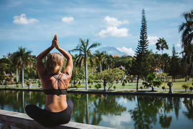 A woman practises yoga in an exotic location by a poolside A woman practises yoga in an exotic location by a poolside